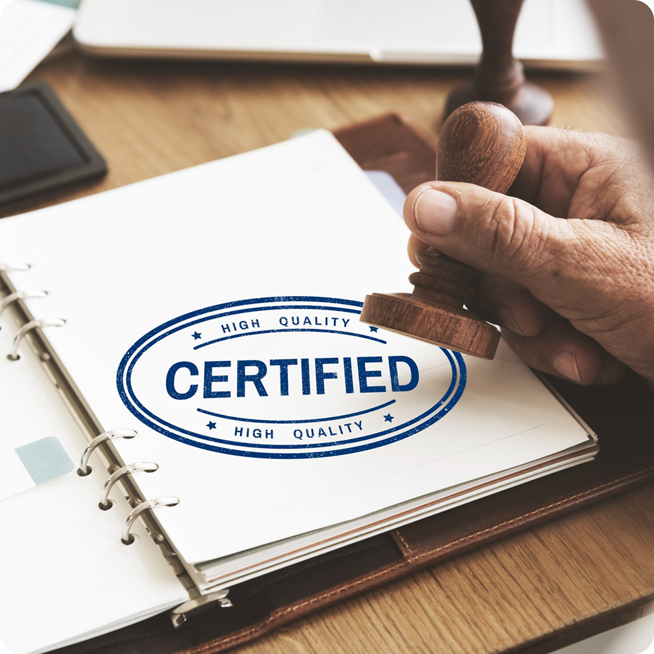 Hand stamping a 'CERTIFIED' seal on a document with a wooden stamp