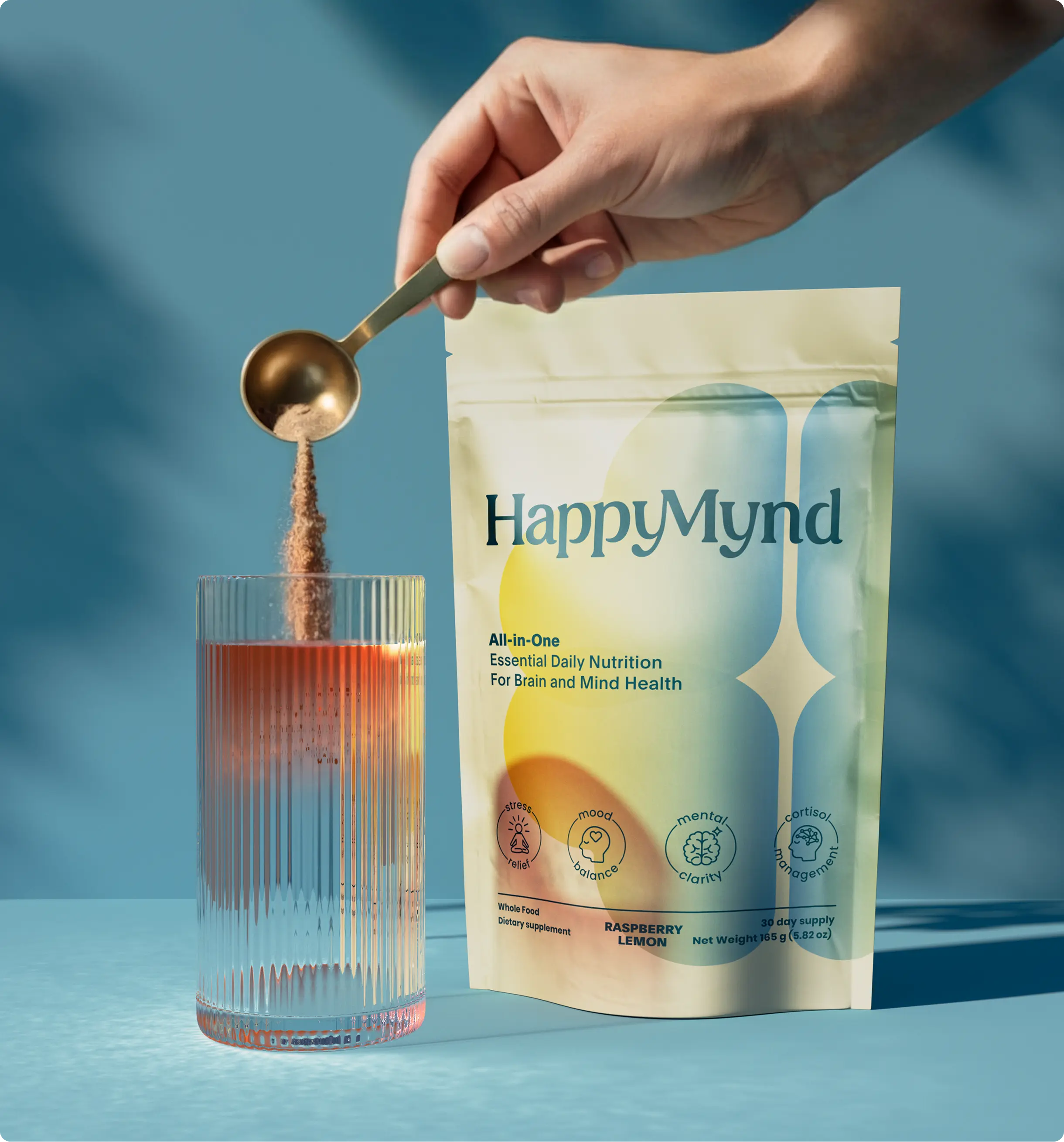 Hand pouring HappyMynd Nutrition for Brain into a glass, with the product package in the background